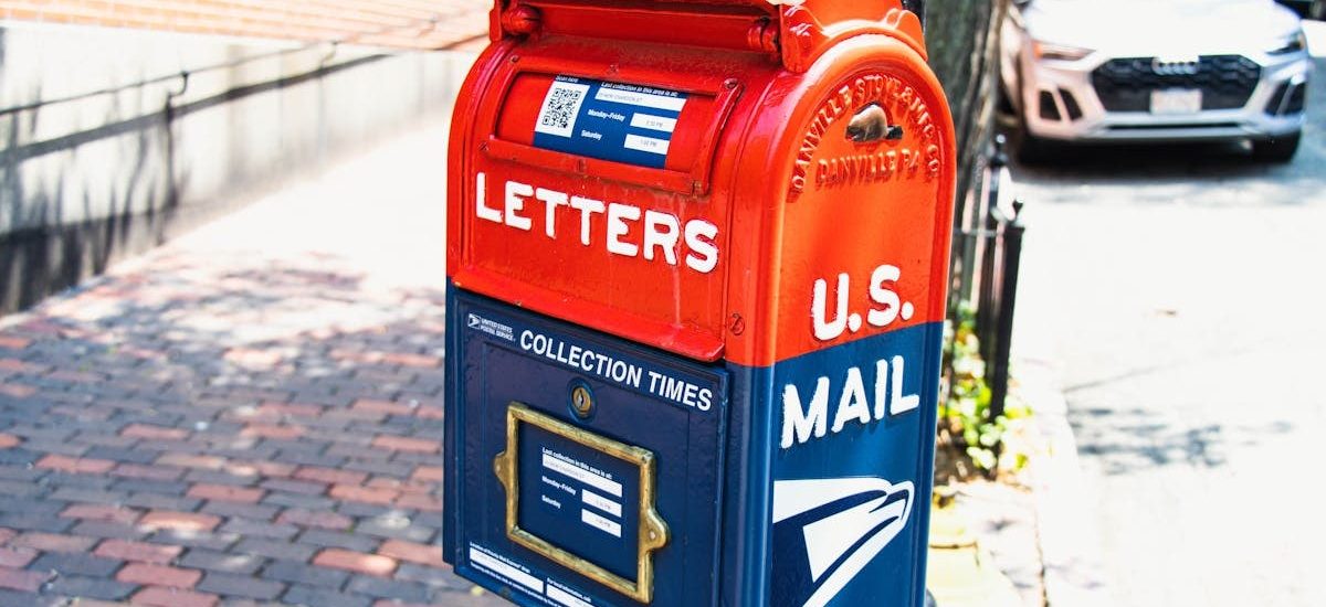 Vibrant U.S. mailbox on a city sidewalk with a parked car, conveying a classic urban scene.