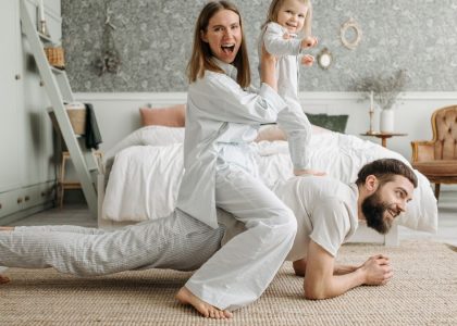 A cheerful family enjoys bonding and playing together on a cozy morning in a stylish bedroom.